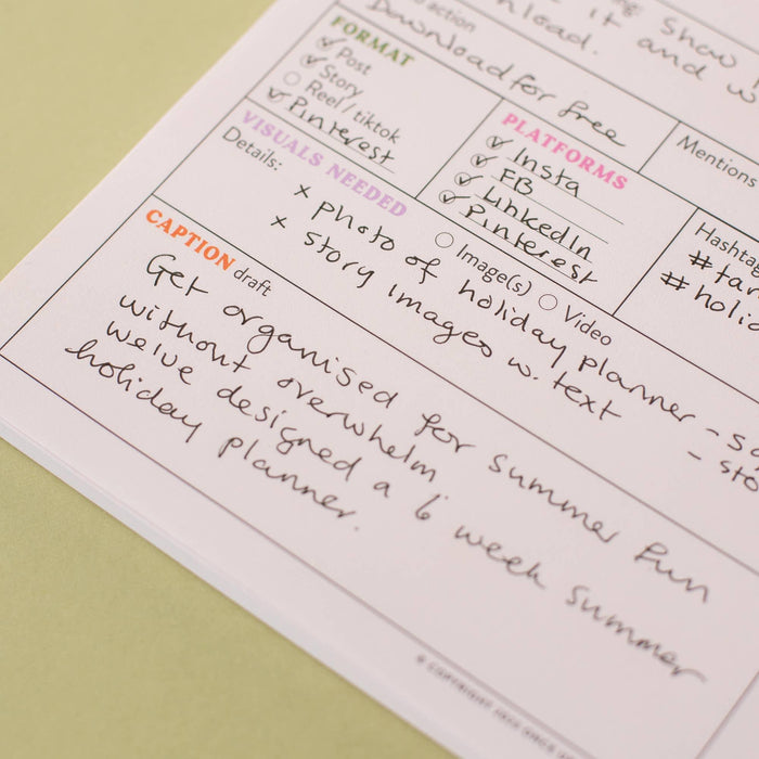 Close-up view of a filled-in content planner page showing format checkboxes for post/story/TikTok/Pinterest, platform selections including Instagram and LinkedIn, and handwritten caption text. Pink and orange section headers on white recycled paper against a sage green background.