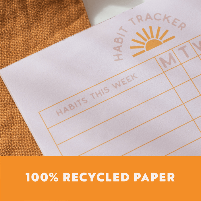 Weekly Habit Tracker made from 100% recycled paper, featuring gold foil sunburst logo and eco-friendly construction for conscious entrepreneurs