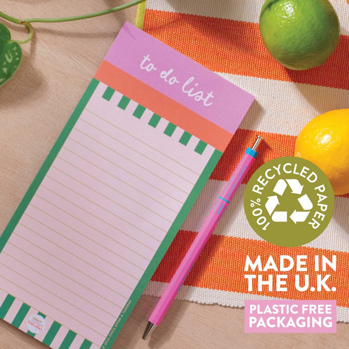 The Cabana Stripe To Do List Pad displayed with product badges highlighting '100% Recycled Paper', 'Made in the UK', and 'Plastic Free Packaging'. Shown on an orange striped cloth with a pink pen, lemon, and plant leaf