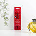 Red VENT For Change recycled pen packaging displayed against a white background with decorative yellow glass bottle and green plant stem, showcasing sustainable stationery design.