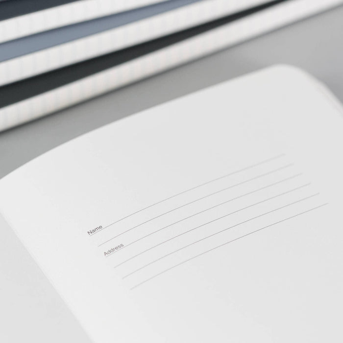 Close-up detail of ivory-coloured lined pages inside VENT notebook, showing name and address fields with subtle grey ruling lines against white paper.