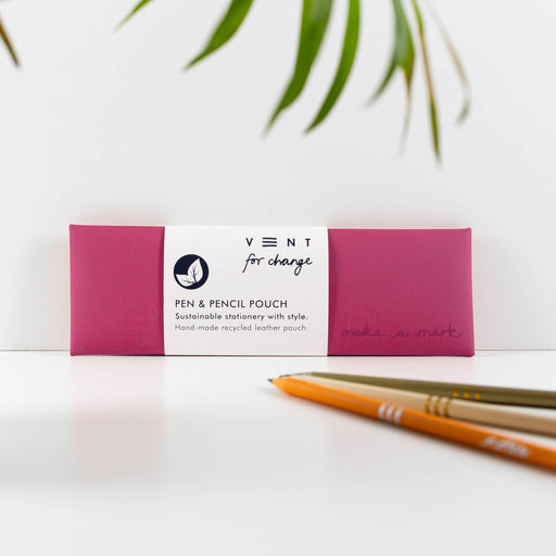 VENT sustainable pink leather pen and pencil case with Make a Mark embossing, shown with wooden pencils against a white backdrop with palm fronds