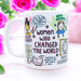 White ceramic mug featuring whimsical illustrated portraits and quotes from influential women including an artistic representation of historical figures, with pink roses in the background. The mug displays hand-drawn text reading 'Women Who Changed the World' along with inspirational quotes and decorative elements in a playful sketch style.